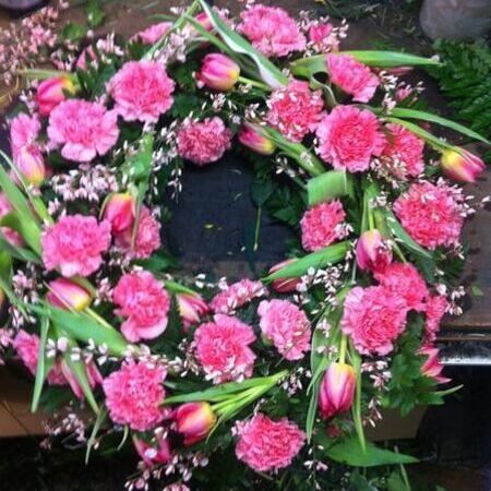 Rund gesteckter Trauerkranz aus pinken Blumen
